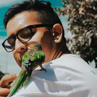 Joaquín P., cuidador de primates, con un ave al hombro (foto de ejemplo)